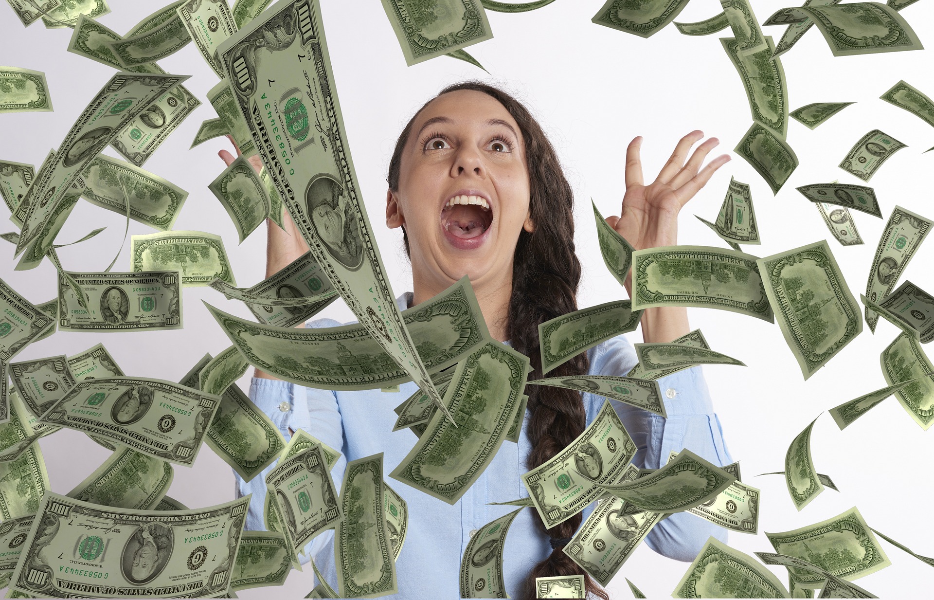 Young lady throwing many $100 bills in the air with a joyous expression on her face.