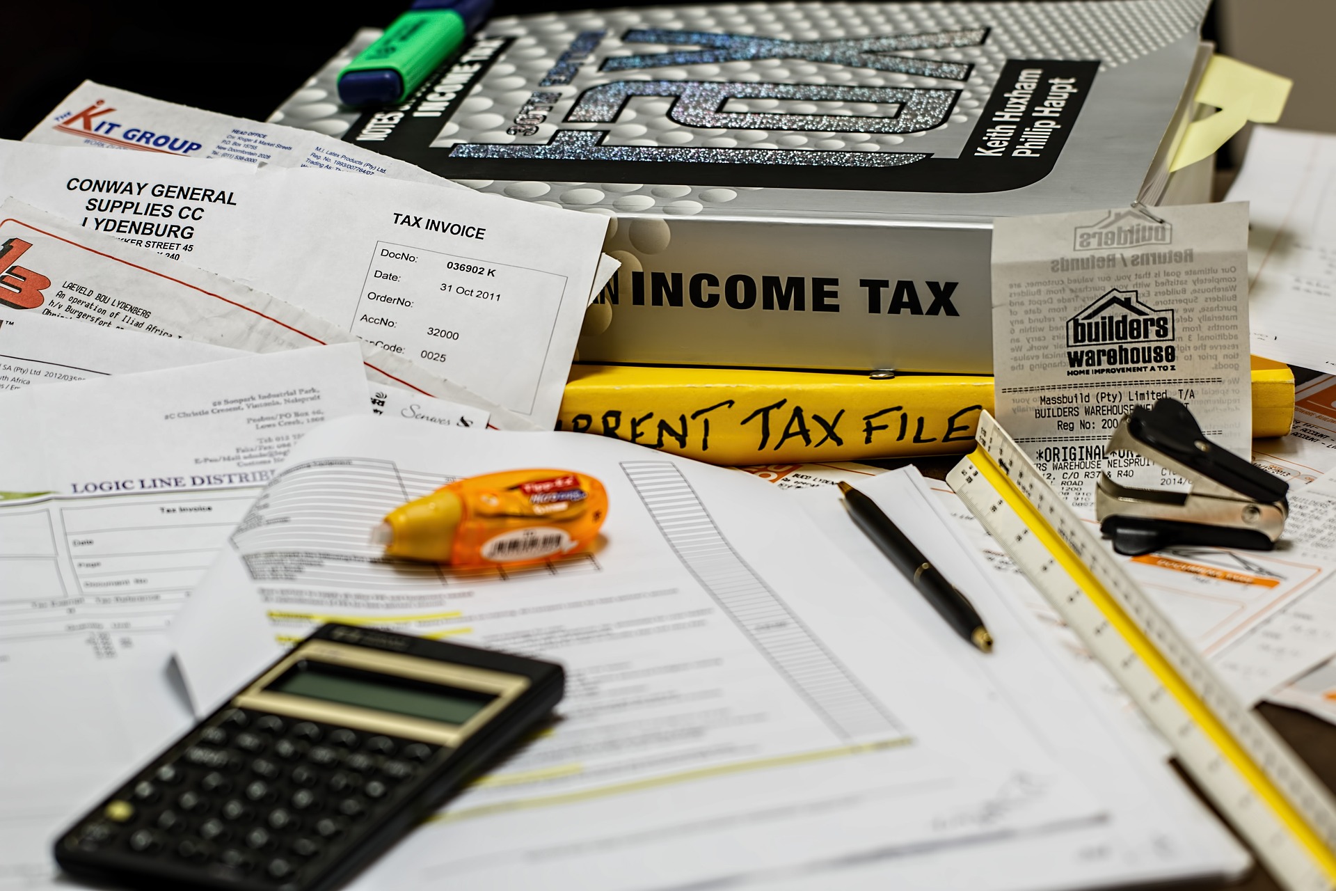 Many bills and invoices pilled up with two large income taxation text books and some receipts and a calculator.